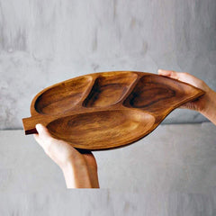 Side view of acacia wood leaf snack tray held in both hands