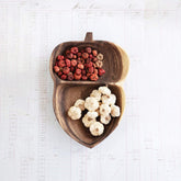 Acorn shaped wooden serving tray with red and white nuts on white table
