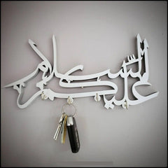 White Assalamualaikum calligraphy key holder with car keys hanging on wall