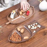 Fish shaped wooden platter tray with sections holding nuts and snacks on table