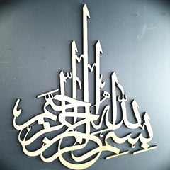 White Bismillah calligraphy wall decor on dark grey wall, angled view