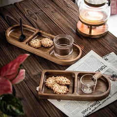 Two oval divided wooden trays with biscuits and tea on rustic table