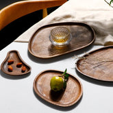 Set of irregular shaped dark wooden serving trays with drink and fruit