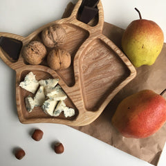 Fox shape wooden platter with walnuts, cheese and pears, top view