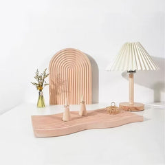 Arched grooved wooden tray and wavy tray with table lamp on shelf