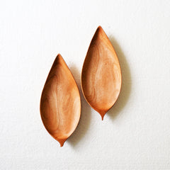 Pair of leaf shaped wooden trays side by side on white surface