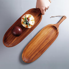 Hand holding long wooden snack platter with dip bowl beside empty platter