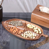 Leaf shaped wooden platter tray filled with nuts and seeds beside tissue box