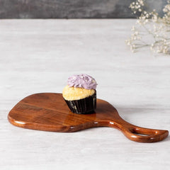 Solid wood serving tray with open handle holding a cupcake on marble surface