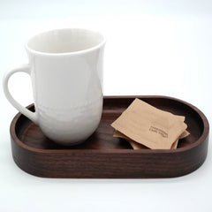 Oval wooden serving tray holding white mug and tea bags