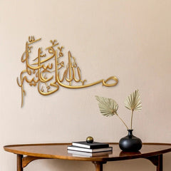 Gold Salawat laser cut calligraphy on warm beige wall above wooden table