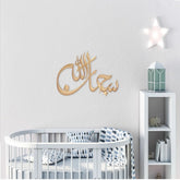 Gold Subhan Allah laser cut calligraphy on white nursery wall above crib
