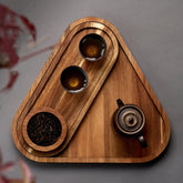 Top view of triangle shaped wooden platter tray with tea bowls and teapot