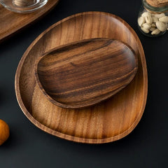Two stacked irregular wooden platters in dark and light wood tones