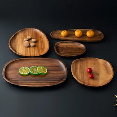 Five irregular oval wooden platters in different sizes on black background, top view