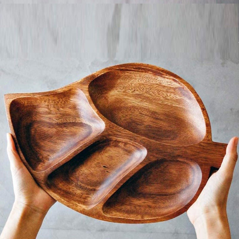Hands holding acacia wood leaf shaped serving tray with four compartments