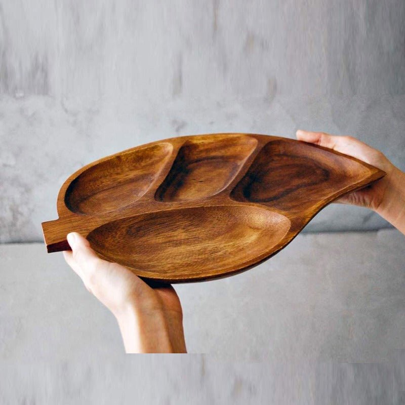 Side view of acacia wood leaf snack tray held in both hands