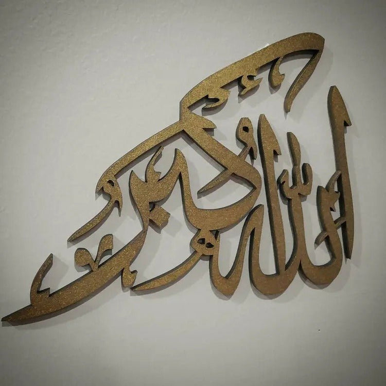 Gold Allah Hu Akbar calligraphy wall decor on beige wall, angled close-up