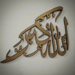 Gold Allah Hu Akbar calligraphy wall decor on beige wall, angled close-up