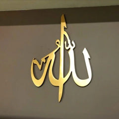 Gold Allah calligraphy wall hanging mounted on grey wall, angled view