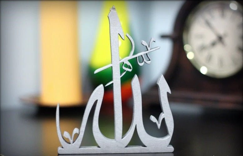 Close-up of white Allah Arabic calligraphy table decor piece near clock