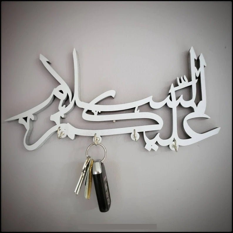 White Assalamualaikum calligraphy key holder with car keys hanging on wall