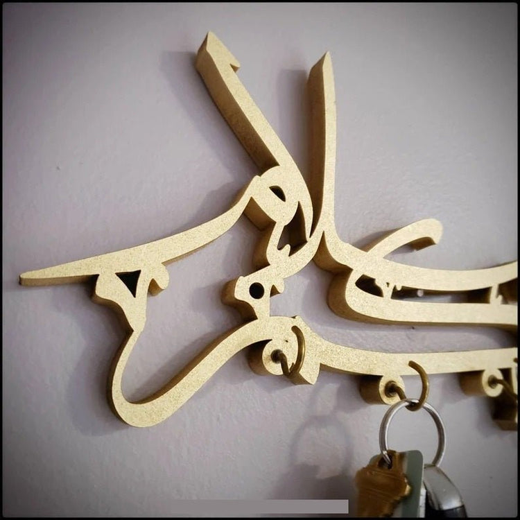 Close-up of gold Assalamualaikum calligraphy key holder hooks with keys