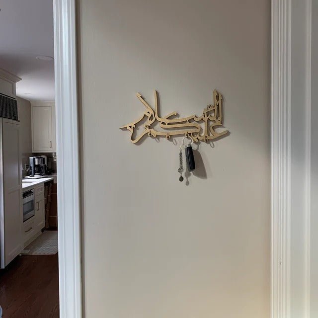 Gold calligraphy key holder mounted on hallway wall near kitchen doorway