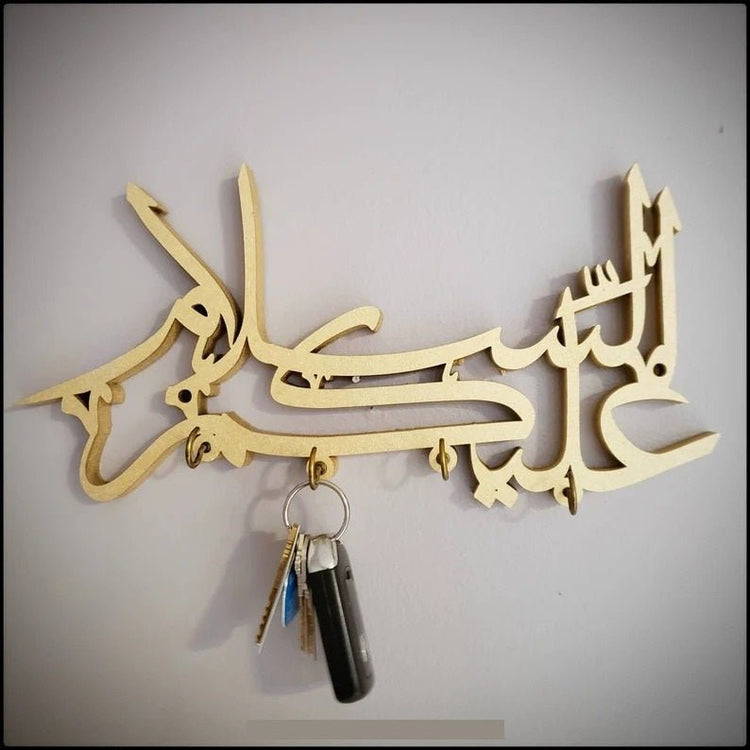 Gold Assalamualaikum Islamic calligraphy key holder with keys on grey wall