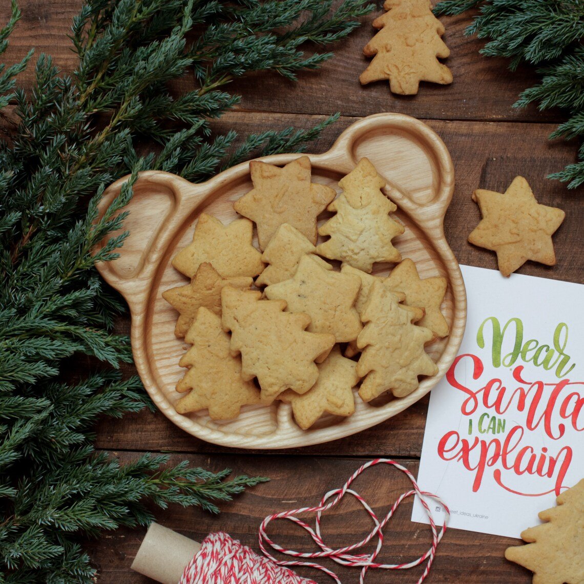 Bear wooden serving platter full of cookies with pine branches, festive setting