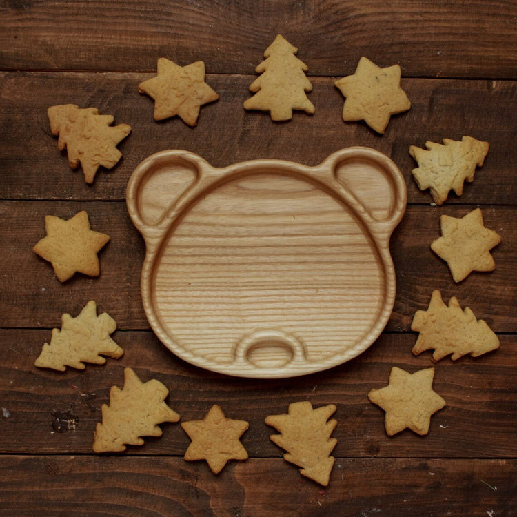 Bear shape wooden tray surrounded by star and tree shaped cookies