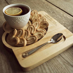 Close-up of coffee cup, swirl pastry and spoon on wooden serving tray