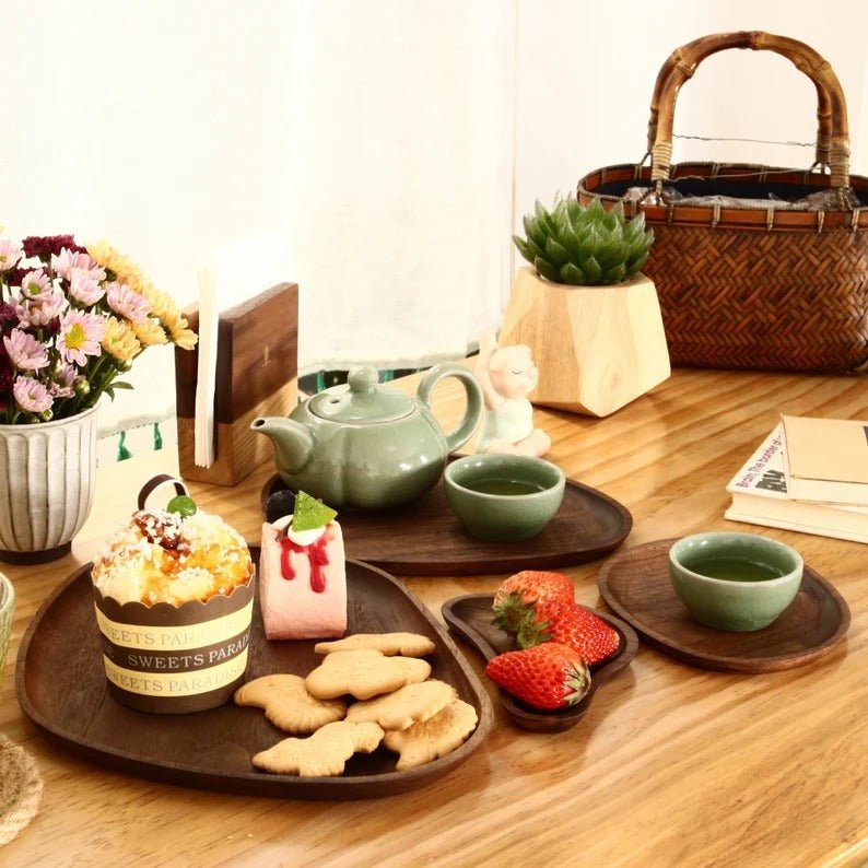 Wooden serving trays with tea set, cookies and cake on table
