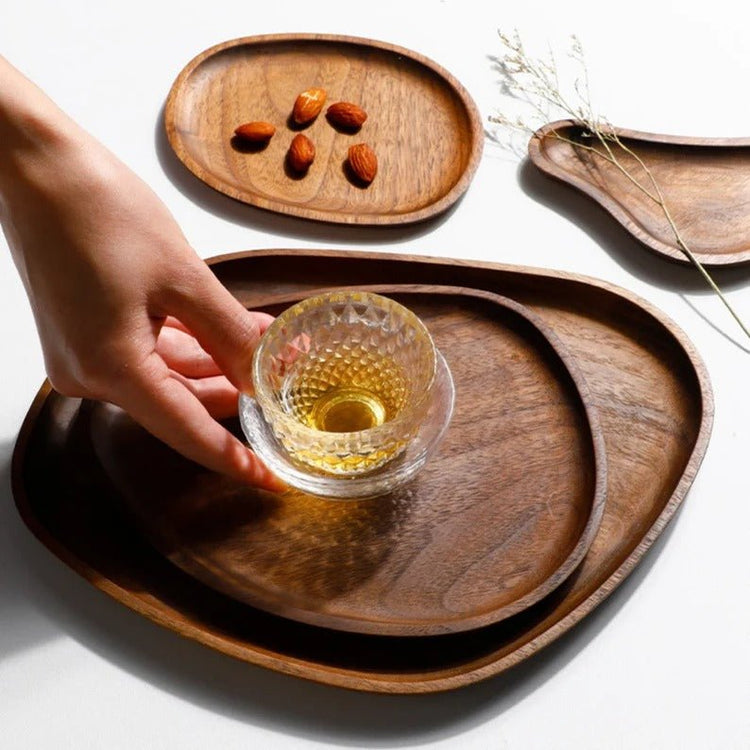 Hand placing glass on stacked irregular wooden serving trays