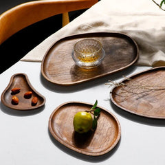 Set of irregular shaped dark wooden serving trays with drink and fruit
