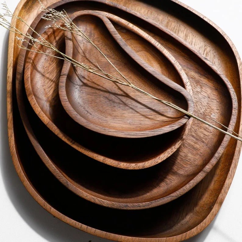 Nested stack of contorted dark wooden serving trays with dried stem