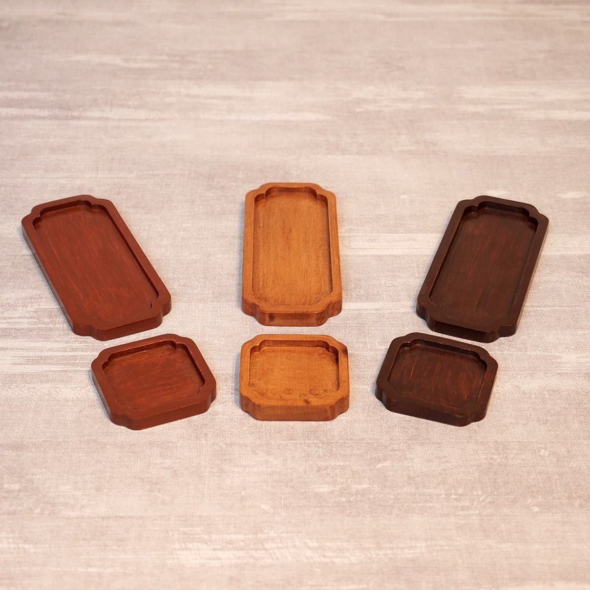 Six empty wooden tea trays in three wood shades arranged in two rows
