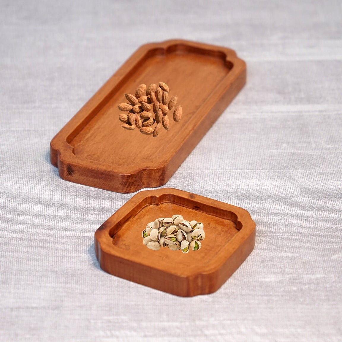 Two light brown octagonal wooden tea trays with nuts, close view