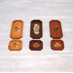 Six wooden tea trays in light and dark finishes holding snacks