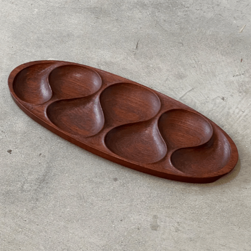 Oval teak wood snack serving tray with five teardrop compartments on concrete surface