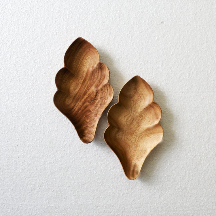 Pair of empty flake shape wooden trays with wavy edges on white surface