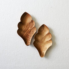Pair of empty flake shape wooden trays with wavy edges on white surface