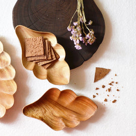 Two flake shaped wooden platters holding crackers beside dried flowers