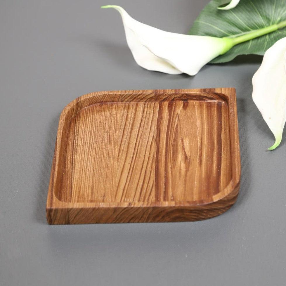 Single square wooden serving platter tray with grooved lines beside white lily