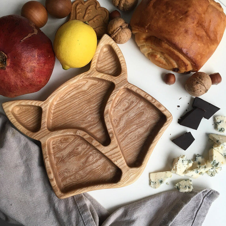Dark finish fox shape wooden tray with apples, lemon and chocolate around it