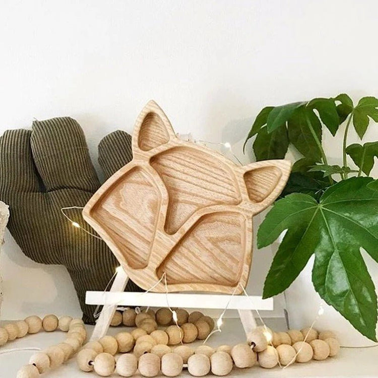 Fox wooden serving tray standing on shelf beside beads and plant