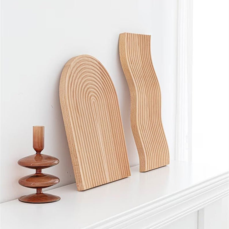 Arched and wavy grooved wooden trays leaning against white wall