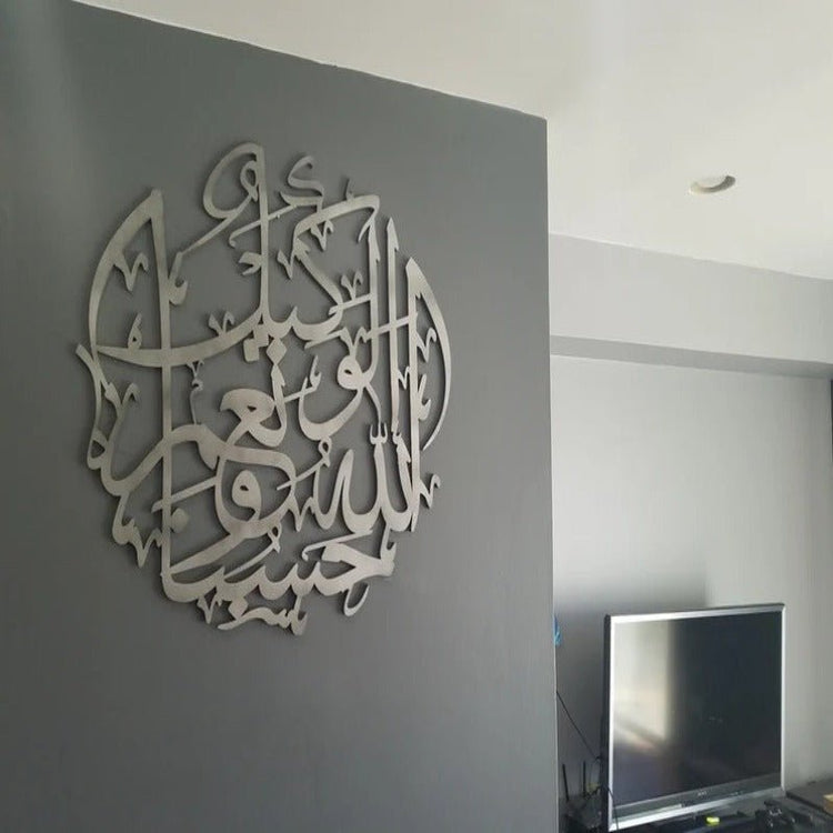Silver HasbunAllah calligraphy wall decor on dark grey wall near TV