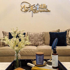 Gold Hasbunallahu laser cut calligraphy above beige sofa in living room