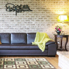 Black Hasbunallahu calligraphy wall art on brick wall above leather sofa